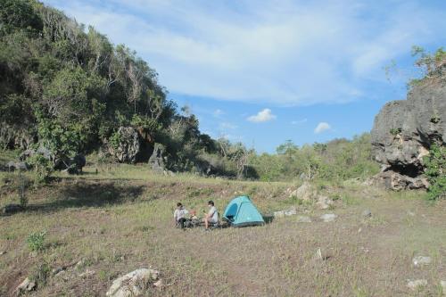 Ngandong的住宿－Wisata Alam Lestari Gunung Semar，三人坐在帐篷旁边的田野里