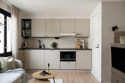 a kitchen with white cabinets and a table in a room at Home Away Apartments Stockholm in Stockholm