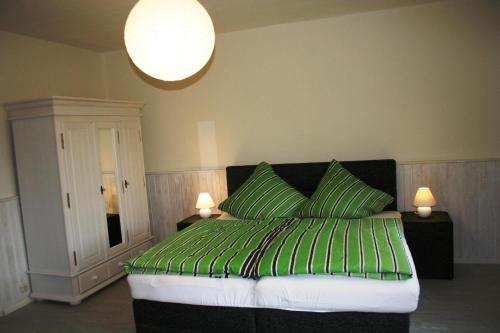1 dormitorio con 1 cama verde y 2 almohadas verdes en Ferienhaus mit Terrasse und Kamin, en Karnin