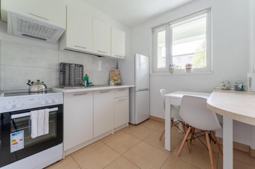 a kitchen with white appliances and a table and a table at Apartament Gold - 2 osobne sypialnie z balkonem - SpaceApart in Jelenia Góra