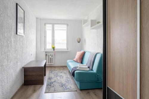 a living room with a blue couch and a table at Apartament Gold - 2 osobne sypialnie z balkonem - SpaceApart in Jelenia Góra