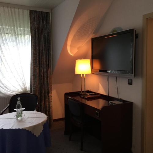 a hotel room with a desk with a television and a table with a lamp at Wolterdinger Hof in Soltau