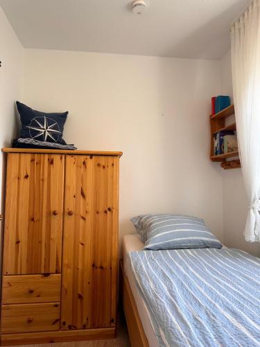 a bedroom with a bed and a wooden cabinet at Ferienwohnung Norddeich: Gemütliche Rückzugsoase für 2-4 Personen in Norden
