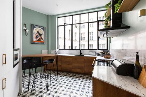 une cuisine avec une fenêtre et un comptoir avec des tabourets dans l'établissement Elégant appartement familial à Paris, à Paris
