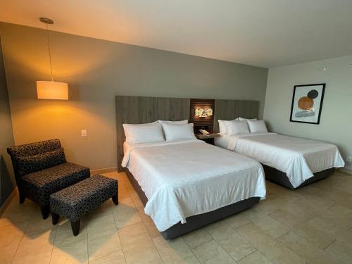 a hotel room with two beds and a chair at Holiday Inn Express Mérida by IHG in Mérida