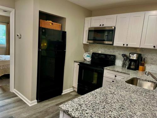 a kitchen with a black refrigerator and white cabinets at London Towne Bungalow Wloft - Walk To The Beach! in Edgewater