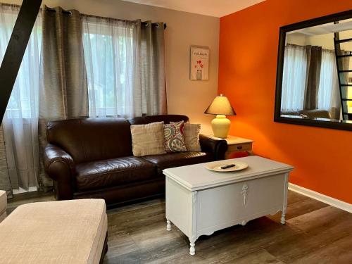 a living room with a leather couch and a mirror at London Towne Bungalow Wloft - Walk To The Beach! in Edgewater