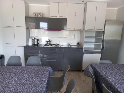 a kitchen with white cabinets and a sink and two tables at SielAnka in Uniejow