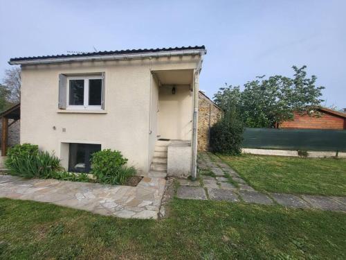 ein weißes Haus mit einer Tür in einem Hof in der Unterkunft Le studio in Béhoust