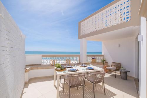 a balcony with a table and chairs and the ocean at Casa na Muralha - Beach front - Rooftop Jacuzzi by DreamvillasAlbufeira in Albufeira