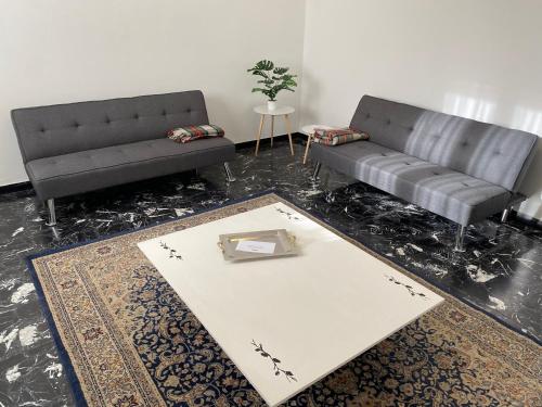 una sala de estar con 2 sofás negros y una alfombra en Appartamento 7 Laghi, en Lomnago