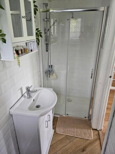 a white bathroom with a shower and a sink at Remarkable 1-Bed Cabin in Dunmow in Great Dunmow