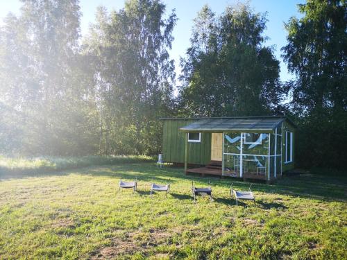 a green cabin with four chairs in a field at Sodyba Brazylija in Taraldžiai