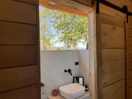 baño con aseo y ventana en Naturnahe Cabina Playa Hermosa, Santa Teresa en Santiago
