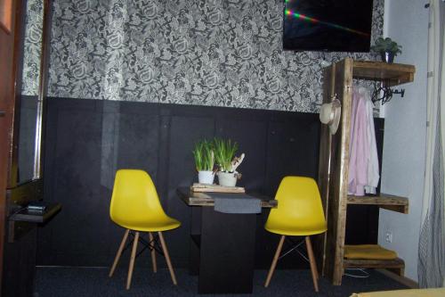 ヤストシェンビャ・グラにあるPokoje Goscinne Na Skarpieの黄色い椅子2脚と植物のあるテーブルが備わる部屋