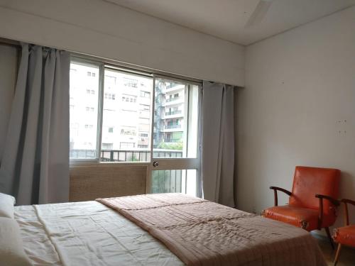 a bedroom with a bed and a chair and a window at Habitaciones con baño compartido en Departamento Mid Century Modern in Mendoza