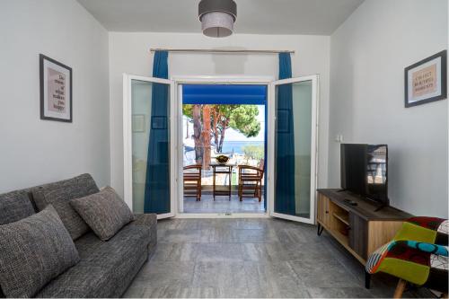 uma sala de estar com um sofá e uma porta de vidro deslizante em Molos Beachfront Apartments in Diakopto em Diakopto