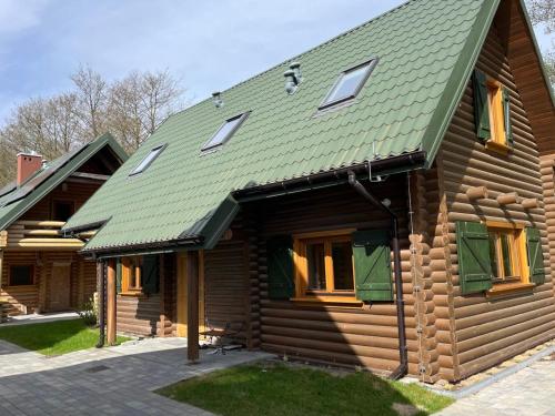 a wooden house with a green roof at Dzikie Gąski in Gąski