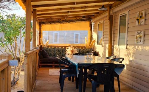 un patio con mesa y sillas en un porche en Mobil-home Le cocon, en Canet-en-Roussillon