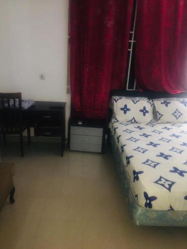1 dormitorio con 1 cama con cortinas rojas y escritorio en Mr Gabriel apartment en Accra