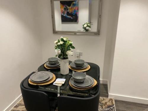 a black table with plates and a vase with flowers at Immaculate 3-Bed Apartment Homes in London in London