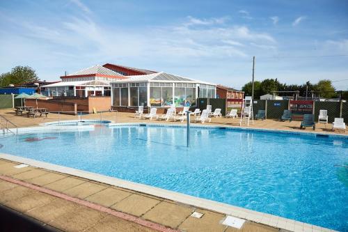 una gran piscina con sillas y un edificio en Morrelo View 24, Cherry Tree Holiday park. en Great Yarmouth