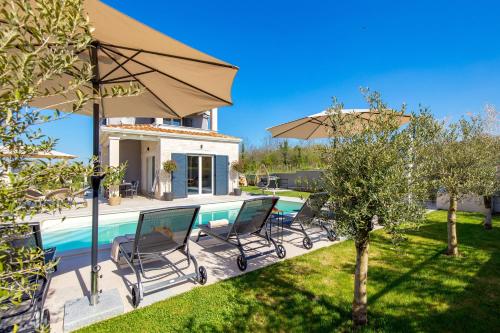 a villa with a swimming pool with chairs and an umbrella at Villa Lente in Muntrilj