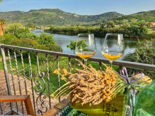 twee glazen wijn op een balkon met uitzicht op een rivier bij Bosa Apartments "House on the River" in Bosa