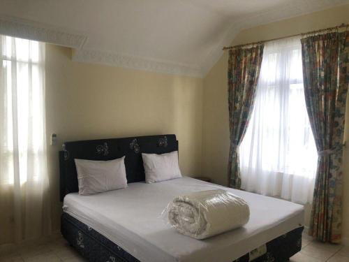 a bedroom with a bed with white sheets and windows at Eton Asia Villas-Kota Bunga in Puncak