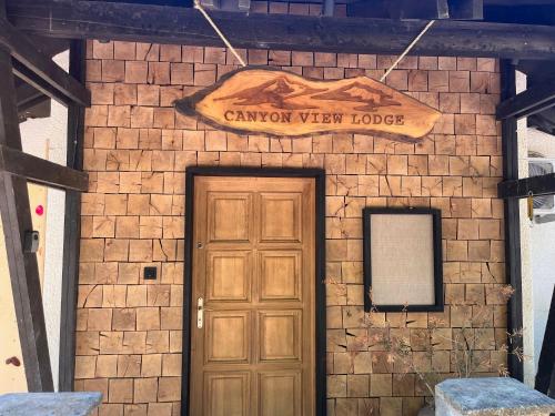 Canyon View Lodge - Matka في ماتكا: باب في مبنى من الطوب مع علامة تشير إلى أن الوادي هو النزل الذي به