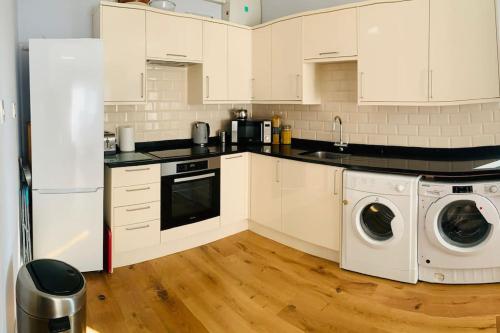 a kitchen with white cabinets and a washer and dryer at Crosby lovely refurbished flat, direct garden access; Wifi in Crosby