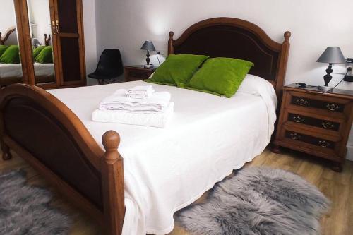 a bedroom with a bed with green pillows and a mirror at Casa Mari&Fernando en Camelle - Costa da Morte in Camelle
