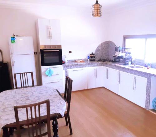 a kitchen with white cabinets and a table and chairs at ferme privé avec piscine in Safi