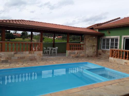 a swimming pool in front of a house at Chácara Nativa in Vargem
