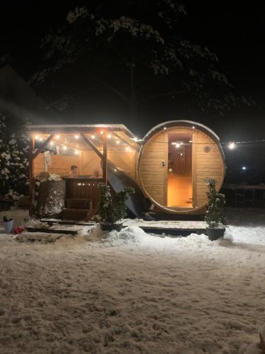a round wooden house in the snow at night at Mazurski dom Brejdyny Sauna i Bania in Mrągowo