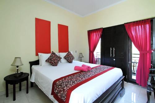 a bedroom with a large white bed with red accents at Ramantika Bali House in Jimbaran