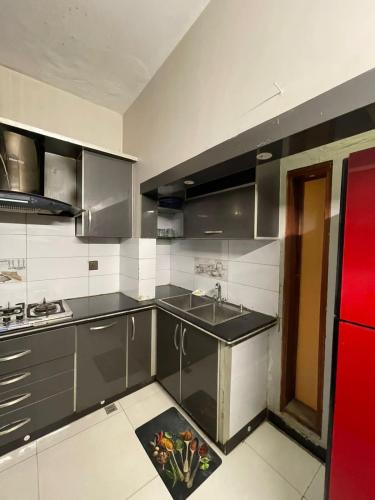 a kitchen with a sink and a red refrigerator at Cozy 2-Bed Portion at Gulshan Iqbal blk 7 in Karachi