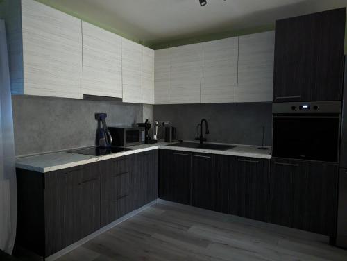 a kitchen with white cabinets and a black appliance at Tsitsipas Apartment in Alexandroupoli