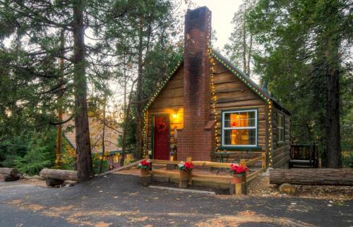 a small log cabin in the woods with flowers on the porch at Arrowhead Pine Rose Cabins in Twin Peaks