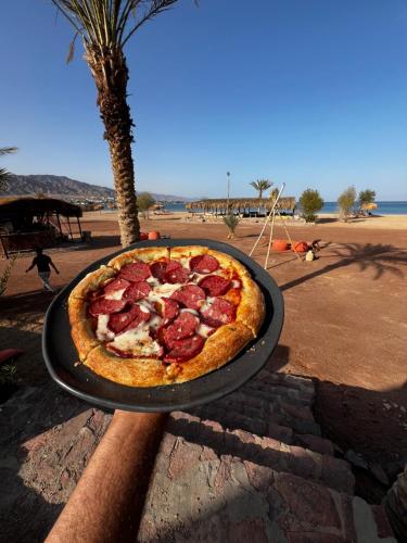 a pepperoni pizza sitting on a table next to a beach at Sukoon Camp in Nuweiba