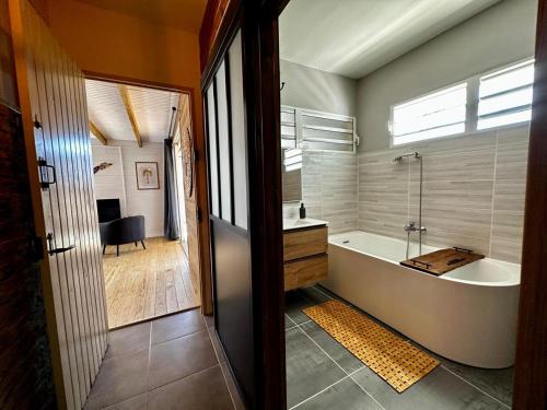 a bathroom with a tub and a sink and a shower at Bungalow L'hibiscus in Sainte-Luce