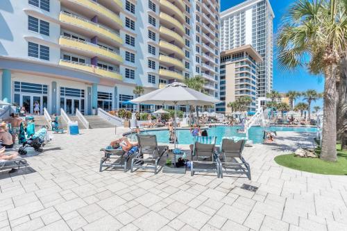 a pool at a resort with people sitting in chairs at Luxurious Oceanfront Haven, Newly Remodeled 1BR with All-New Furnishings at the Wyndham Ocean Walk in Daytona Beach