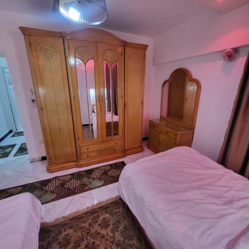 a bedroom with a wooden cabinet and a bed at شقه فى ميامى بالاسكندريه مطله على البحر in Alexandria
