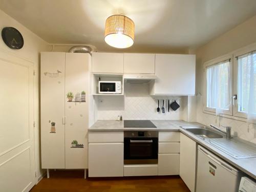 uma cozinha com armários brancos, um lavatório e um micro-ondas em Maisons Alfort - Cosy appartement em Maisons-Alfort