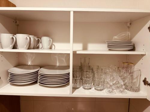 a white cabinet filled with plates and glasses at FELIX LIVING 9, modern & cozy, 3 Zimmer Wohnung, Parkplatz in Salzweg
