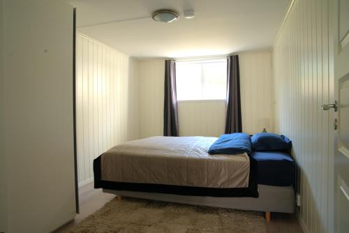 a bedroom with a bed with blue pillows and a window at Spacious apartment in Sarpsborg