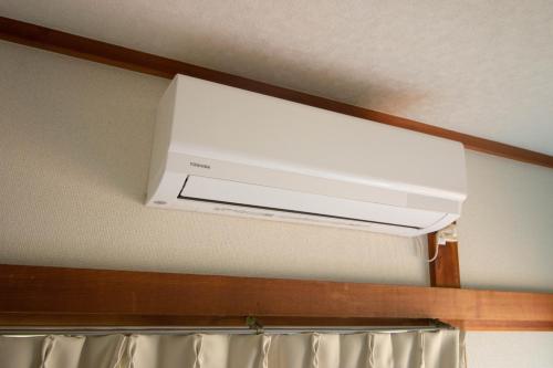 a white air conditioner hanging from a ceiling at Saku House Jujo in Tokyo