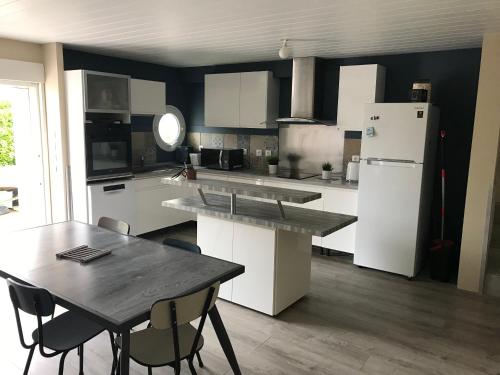 une cuisine avec une table et un réfrigérateur dans l'établissement Maison centre du village, à Grand-Village-Plage