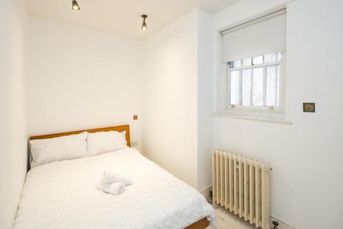 ein Schlafzimmer mit einem weißen Bett und einem Fenster in der Unterkunft Cosy apartment in the Heart of Nottinghill, 2mins to Portobello Road Market, Perfect for family or professionals in London