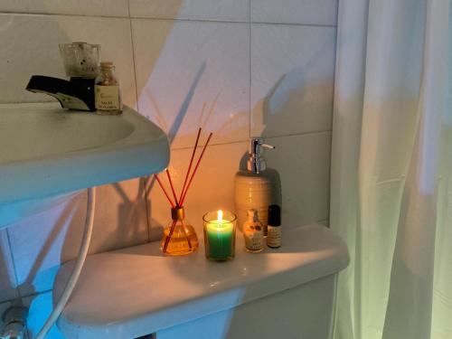 a bathroom shelf with a bottle and a candle at Habitación Independiente y baño privado - RURAL in Girón